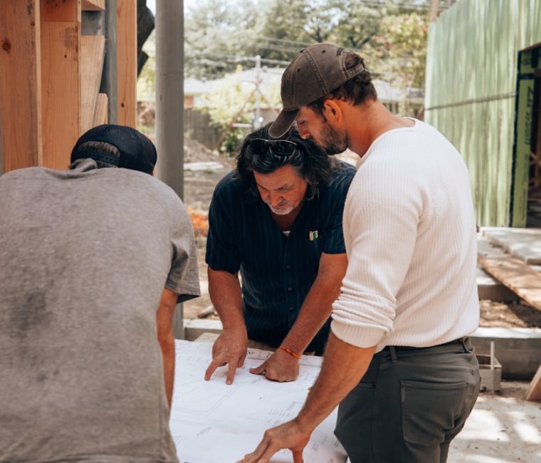 a group of men standing around a white sheet of paper